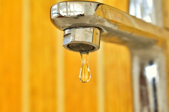a dripping faucet against a yellow background